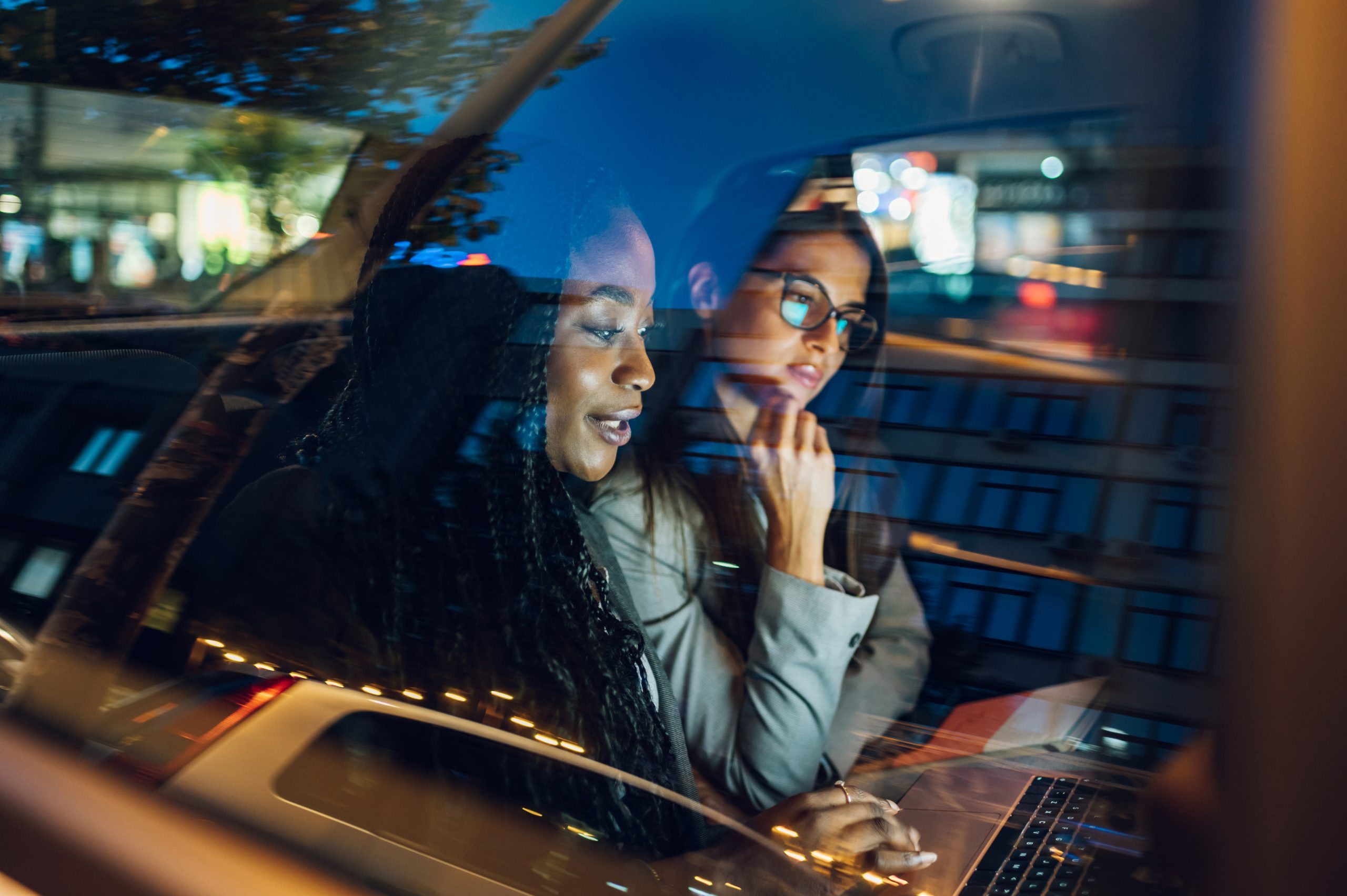 two-multiracial-business-woman-riding-in-a-car-and-2023-11-27-05-22-37-utc